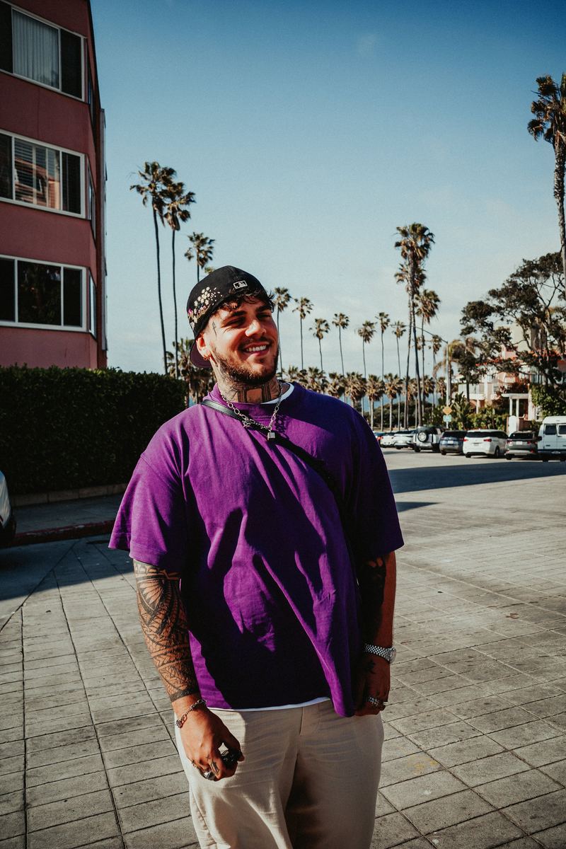 Portrait souriant en t-shirt violet, avenue bordée de palmiers