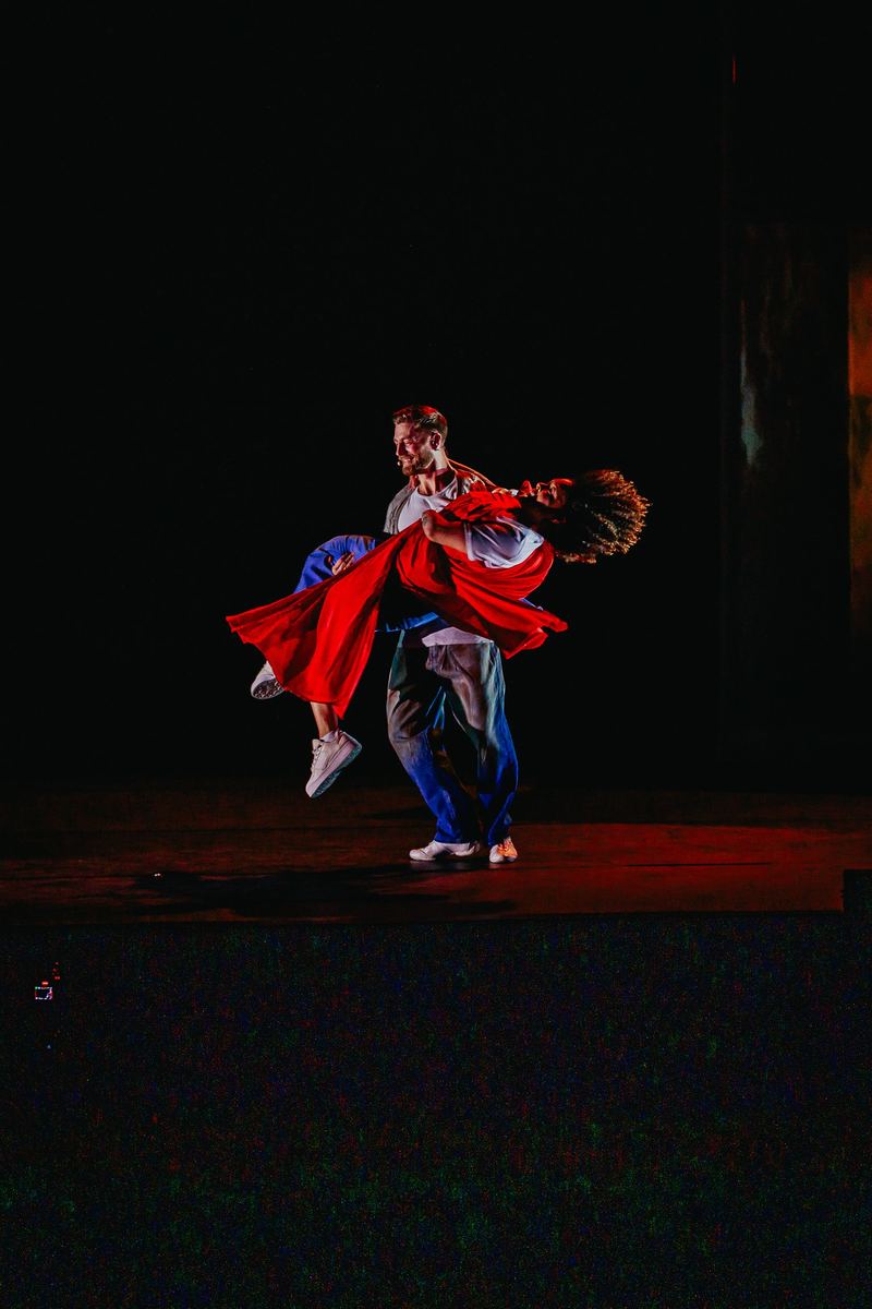 Danseurs enlacés en pleine rotation, robe rouge en mouvement