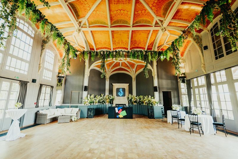 Salle de réception voûtée décorée de guirlandes de feuillage, piste de danse prête