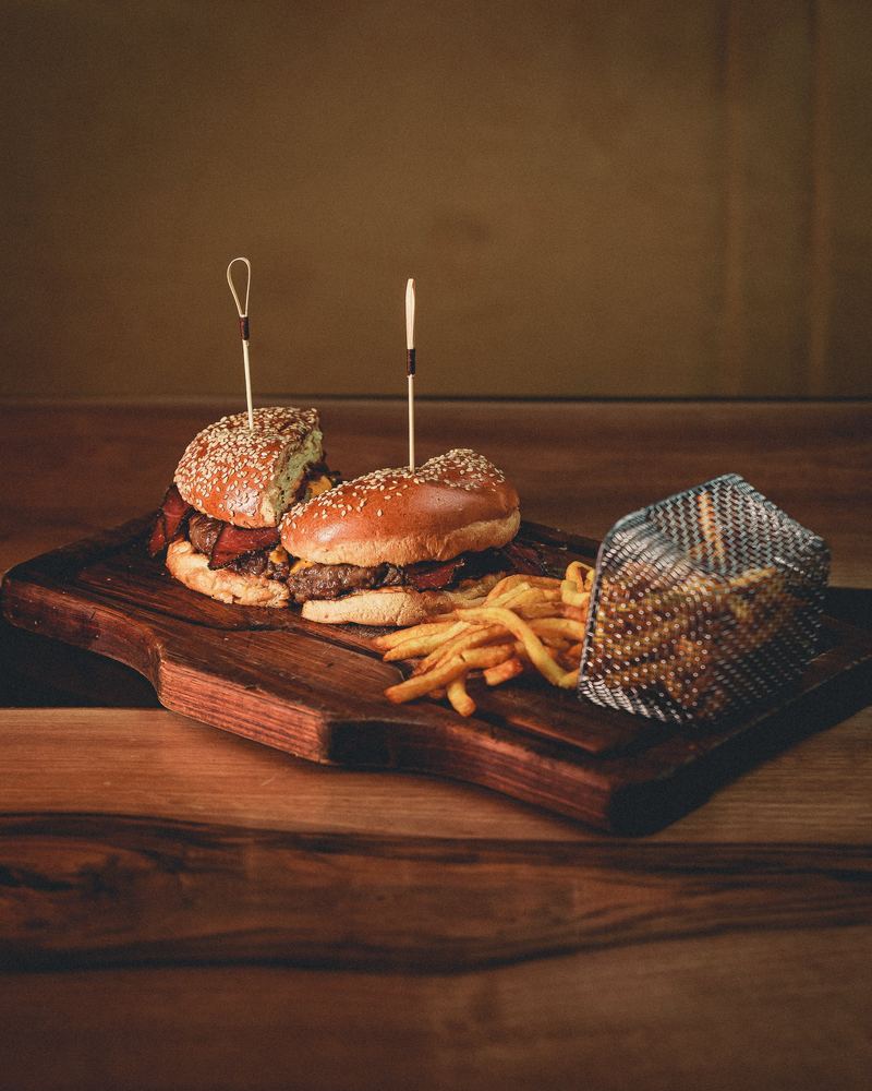 Deux burgers et leur cornet de frites sur planche de bois