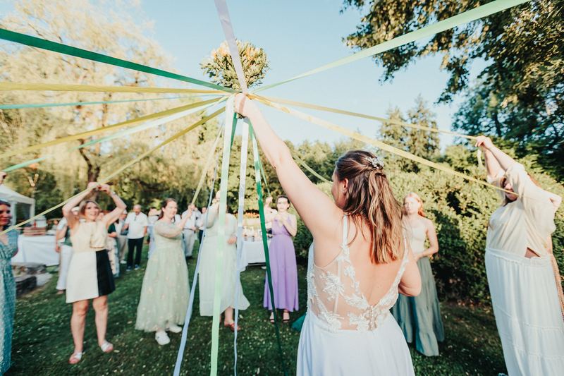 Jeu des rubans : la mariée brandit son bouquet, entourée des invitées