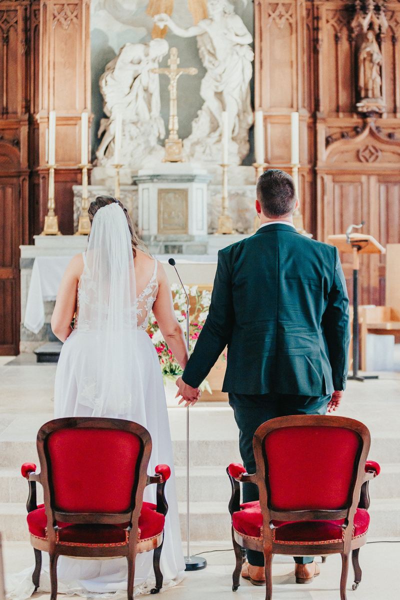 Les mariés de dos devant l’autel de l’église, main dans la main