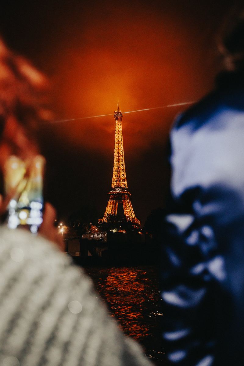 La tour Eiffel illuminée la nuit, aperçue entre deux invités