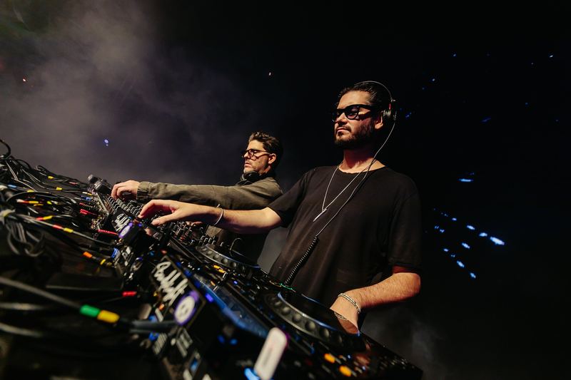 Duo de DJ concentré sur la régie, faisceaux bleus en arrière-plan