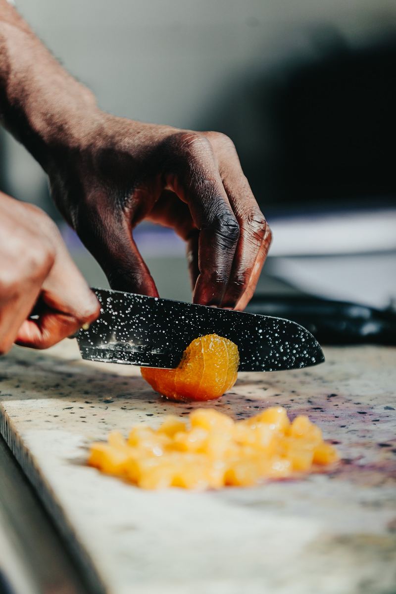 Mains du cuisinier taillant des abricots au couteau, en cuisine