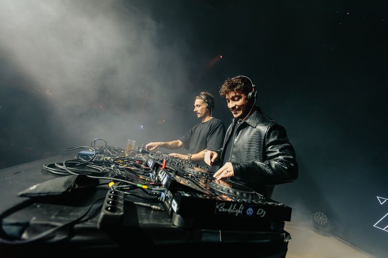 Duo de DJ derrière la régie, fumée et contre-jour sur scène
