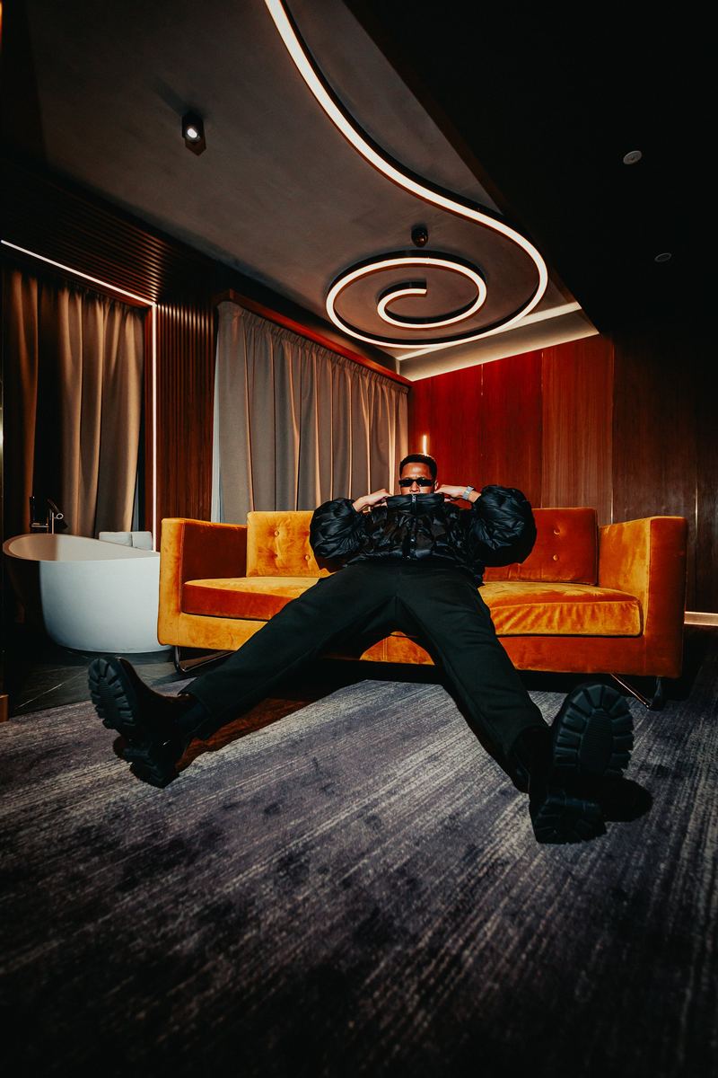 Pose acrobatique devant un canapé orange, sous un plafonnier en spirale