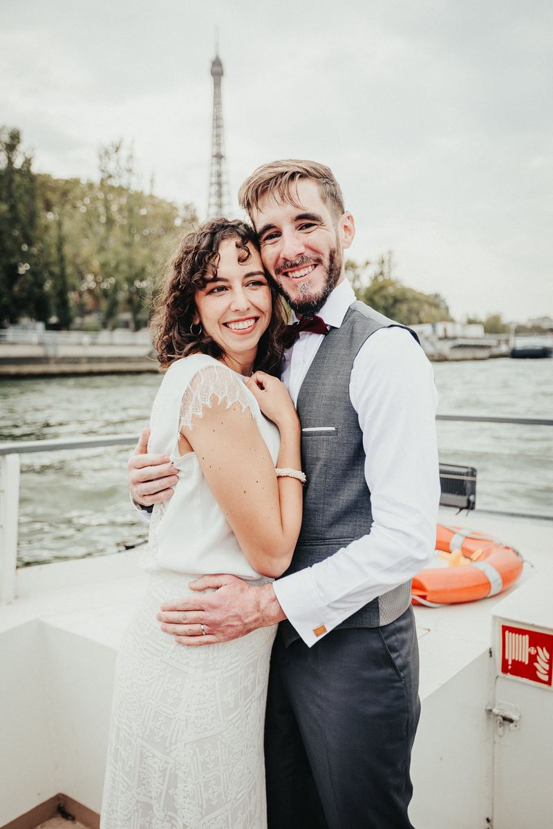 Les mariés enlacés sur le pont du bateau, tour Eiffel en arrière-plan