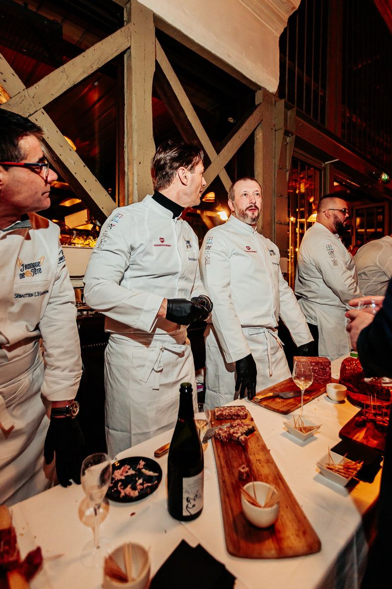 Chefs réunis autour d’un buffet, planche de charcuterie au premier plan