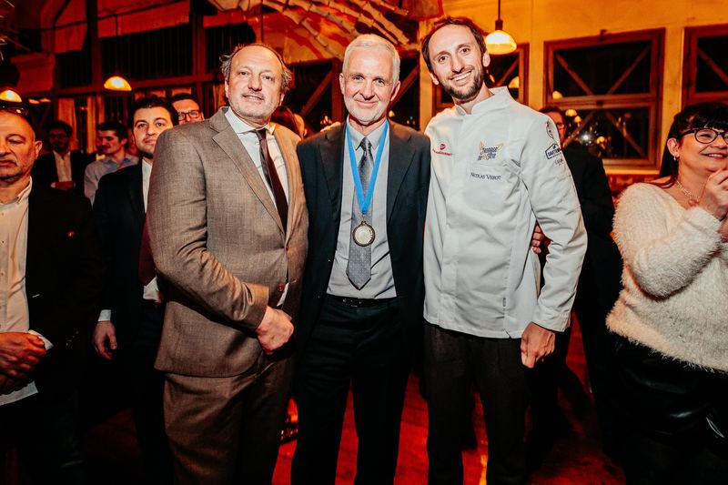 Remise de distinction : trois convives posent, dont un chef en veste blanche