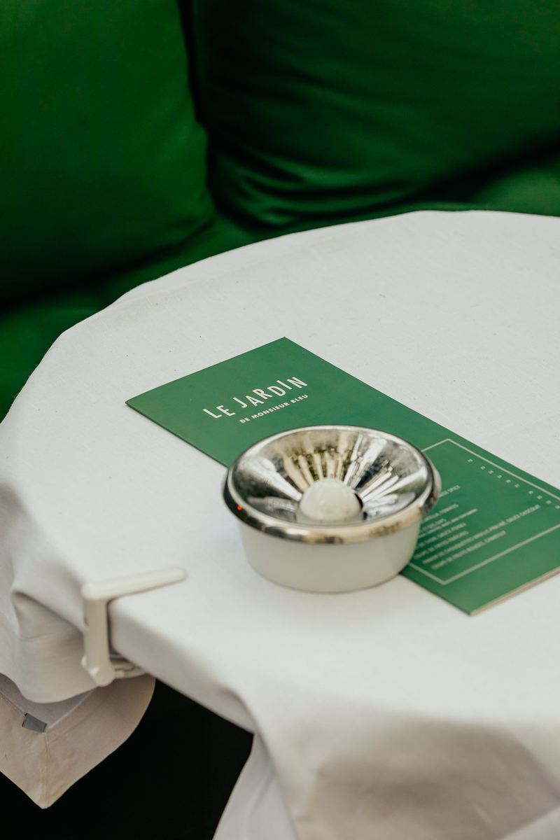 Détail de table : carte du restaurant et coupelle argentée sur nappe blanche