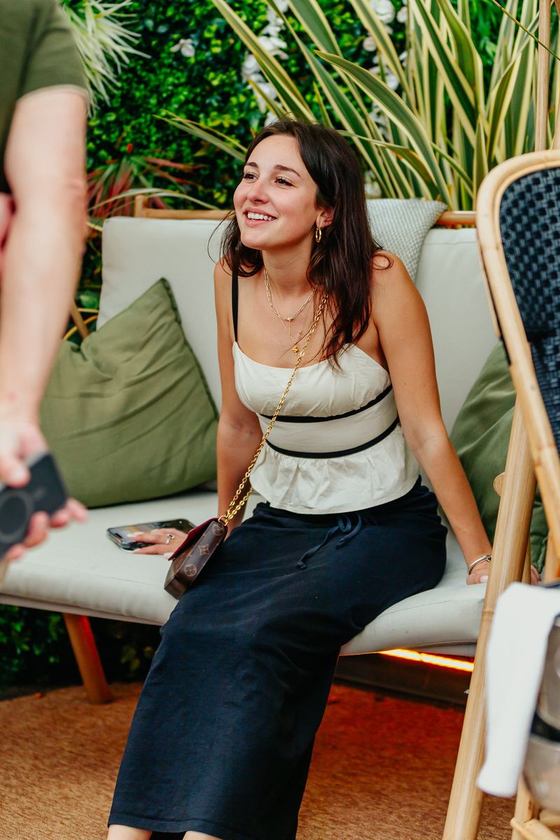 Invitée souriante installée sur une banquette, dans le jardin du lieu