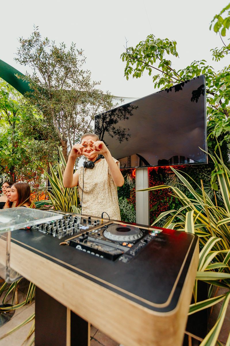 La DJ forme un cœur avec ses mains derrière les platines, en extérieur