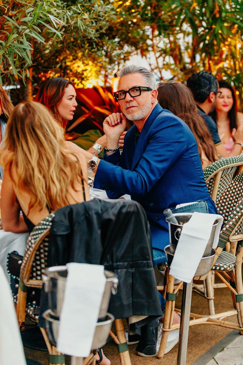 Invité en costume bleu attablé en terrasse au coucher du soleil