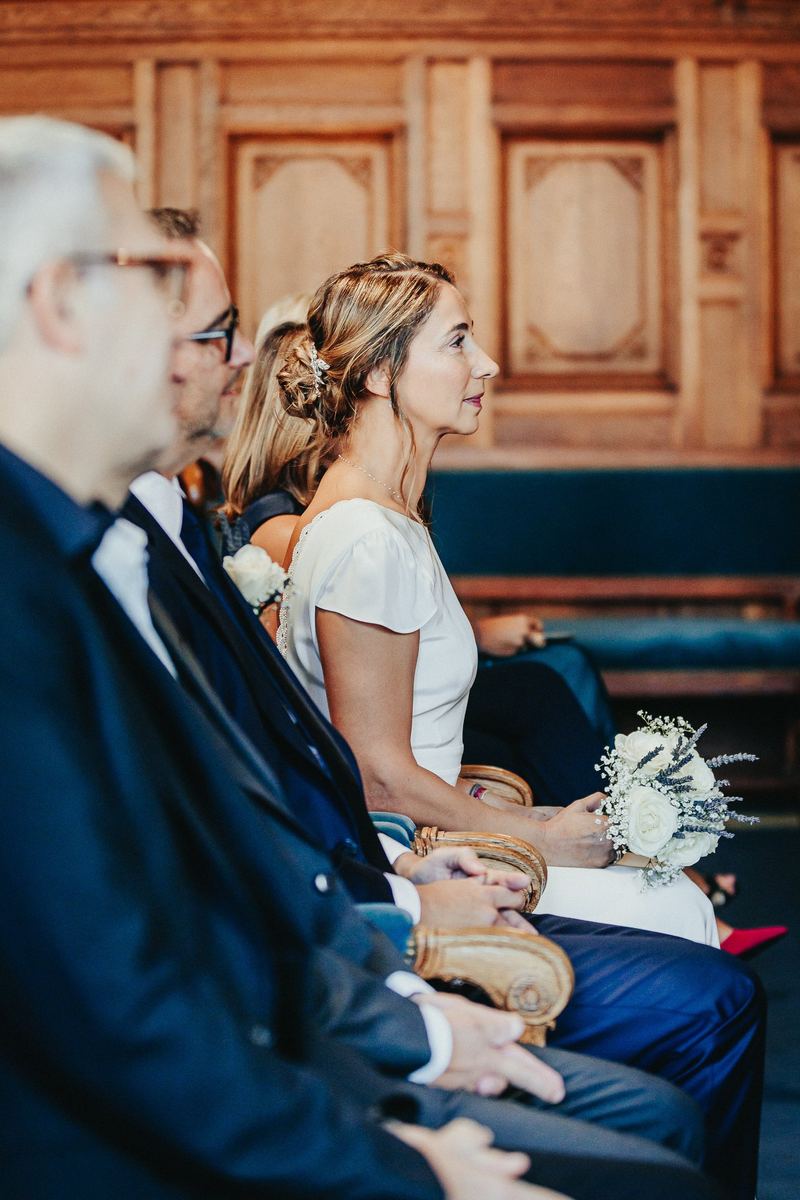 La mariée assise pendant la cérémonie, dans la salle boisée de la mairie