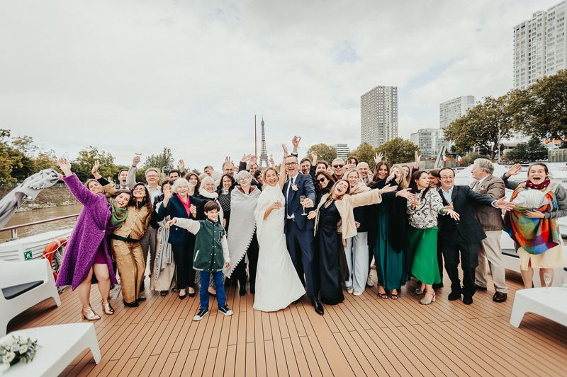 Photo de groupe des invités sur le pont du bateau, tour Eiffel en arrière-plan