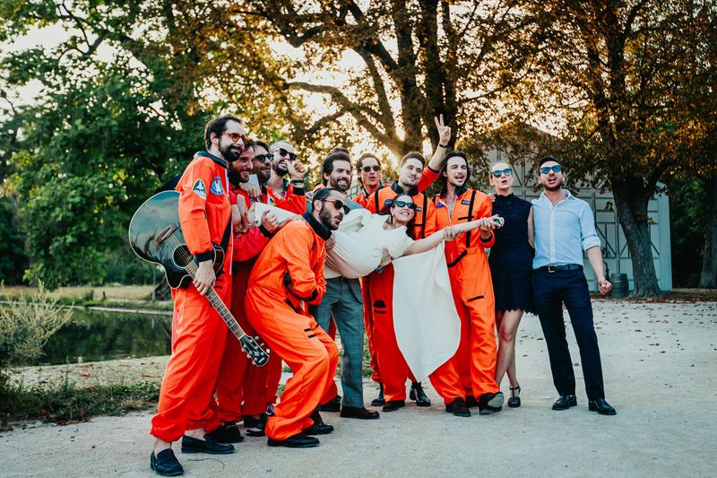 Fanfare en combinaison orange portant la mariée à bout de bras