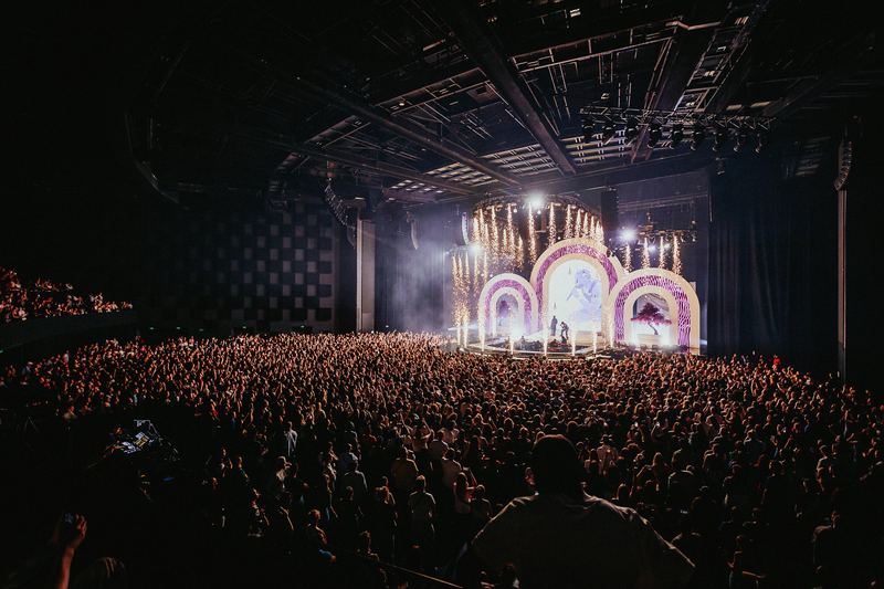 Salle comble face à une scène illuminée lors d’un événement