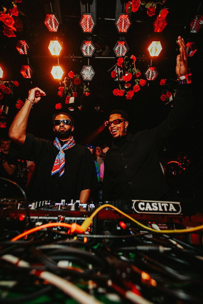 Deux DJ lèvent les bras derrière les platines