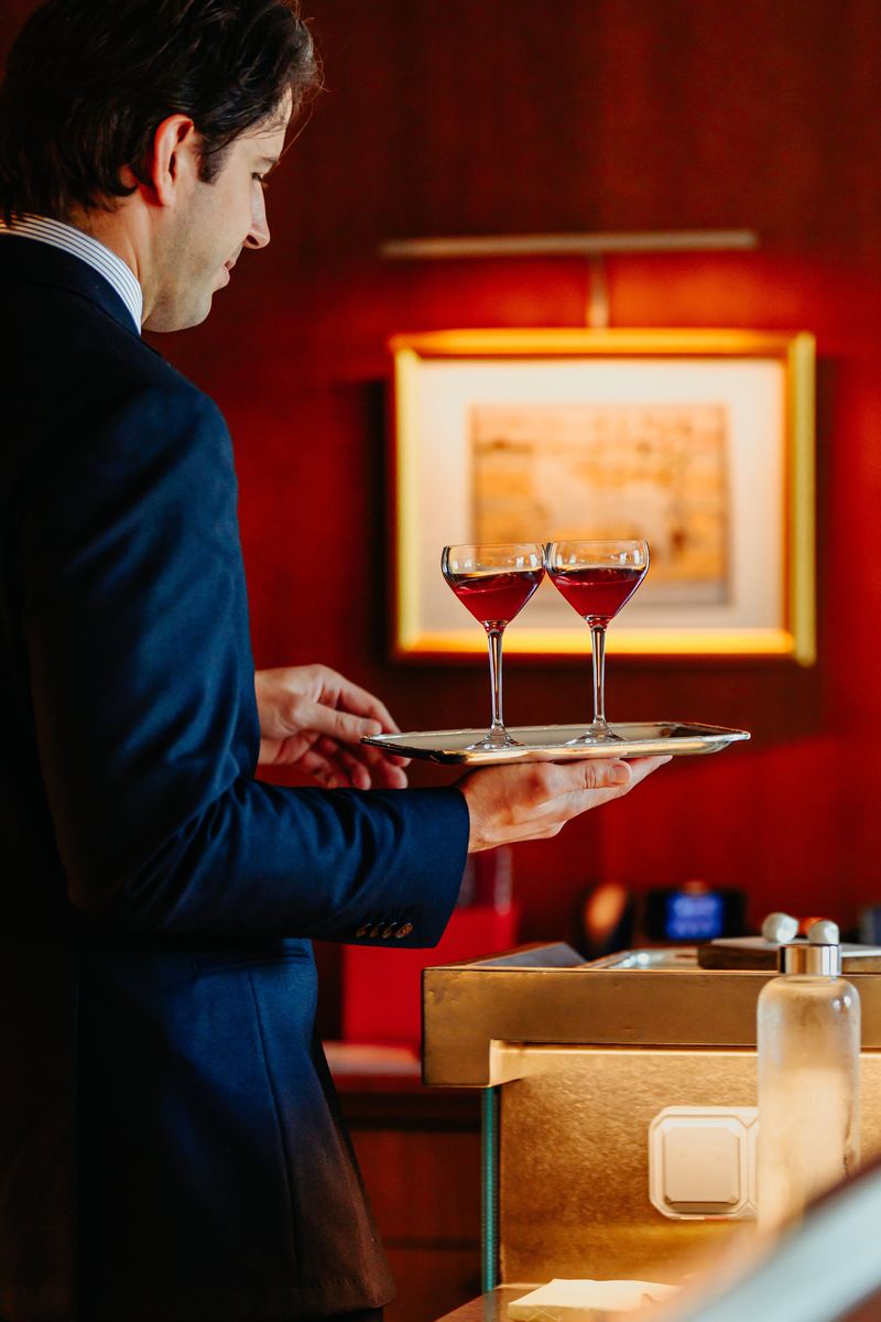 Serveur porte deux cocktails sur un plateau dans une salle boisée