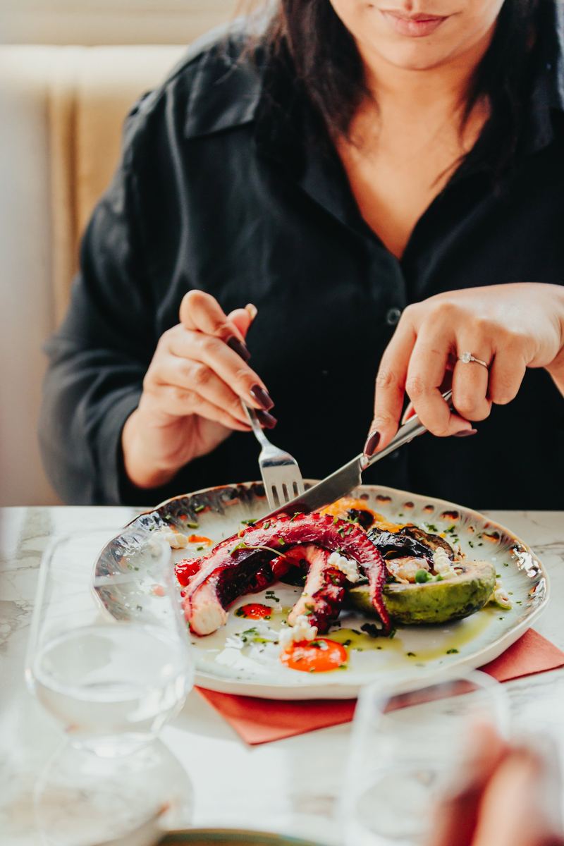 Cliente découpe une assiette de poulpe et avocat au restaurant
