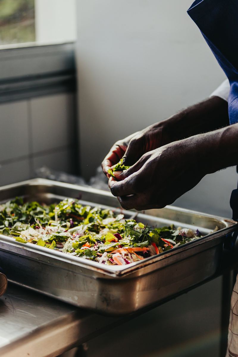 Dressage d’un bac de légumes en cuisine, mains du cuisinier au travail