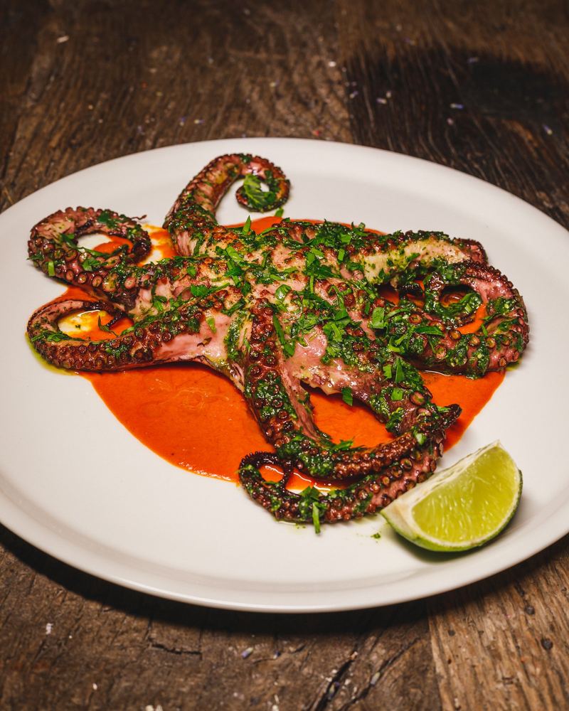 Poulpe grillé sur sauce rouge, quartier de citron vert