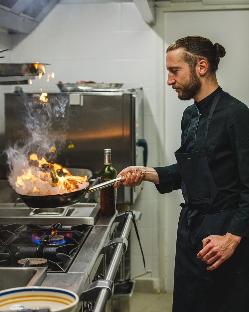 Le chef flambe une poêle sur le piano de cuisson