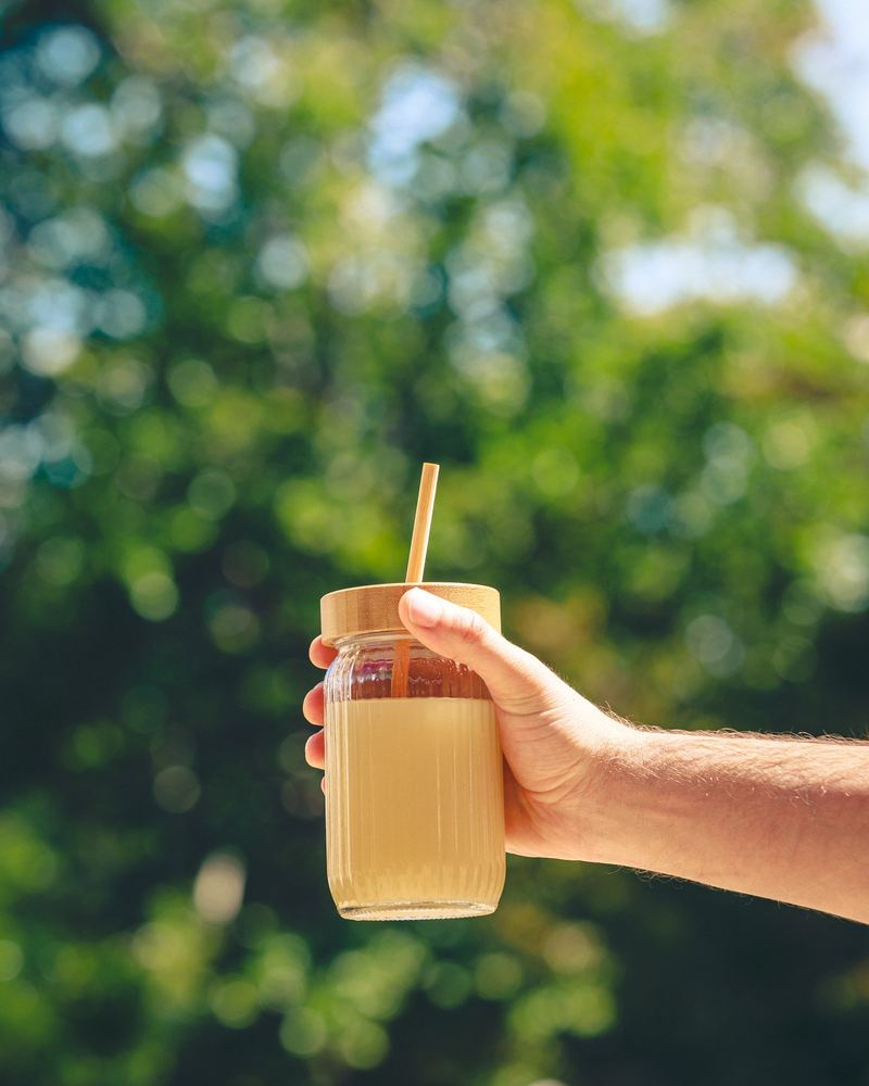 Boisson maison en bocal tenue à bout de bras devant la végétation