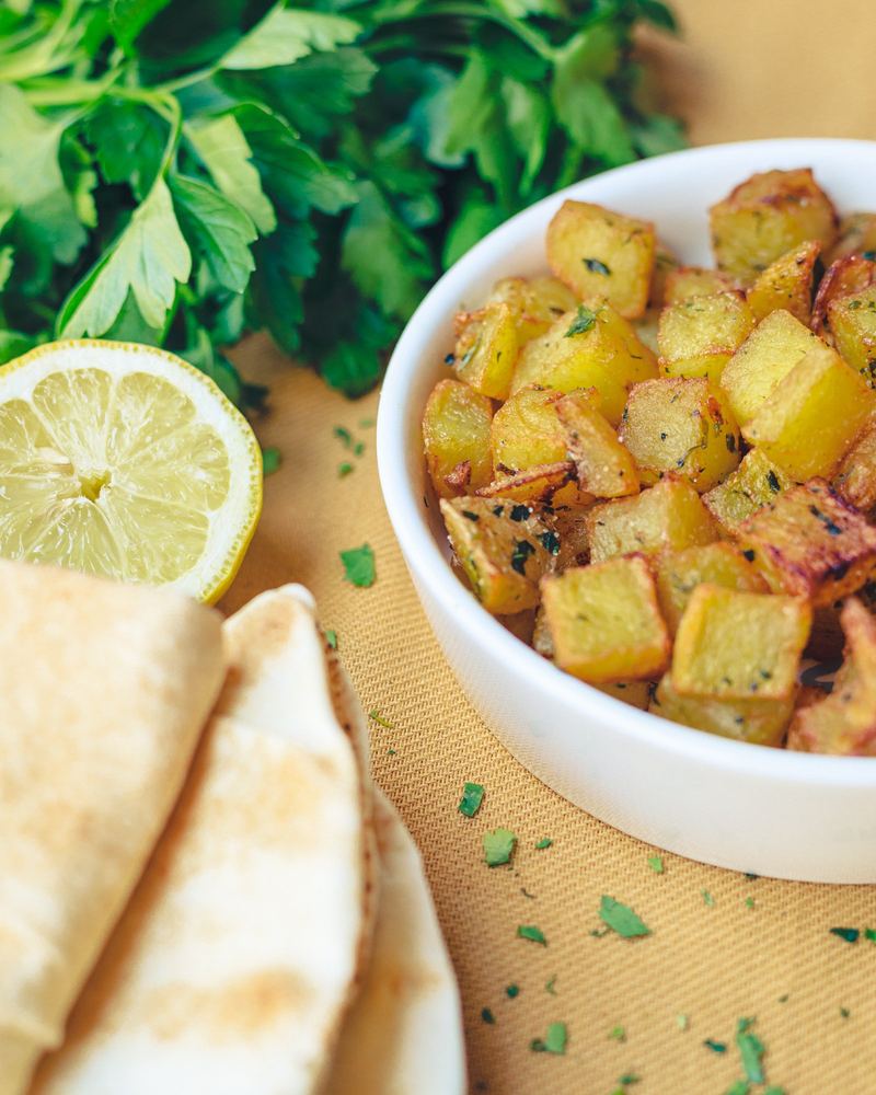 Bol de pommes de terre sautées au persil, pain plat et citron