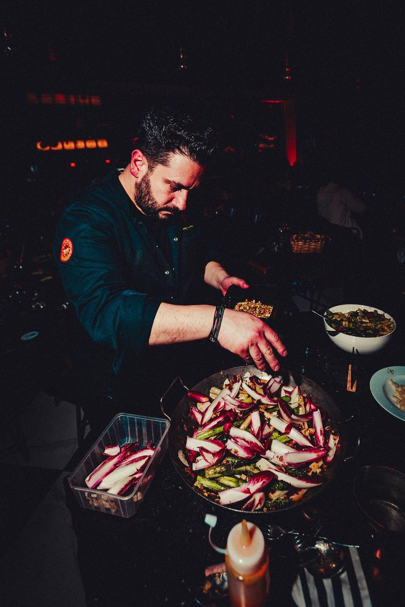 Le chef dresse une poêle d’endives en cuisine ouverte