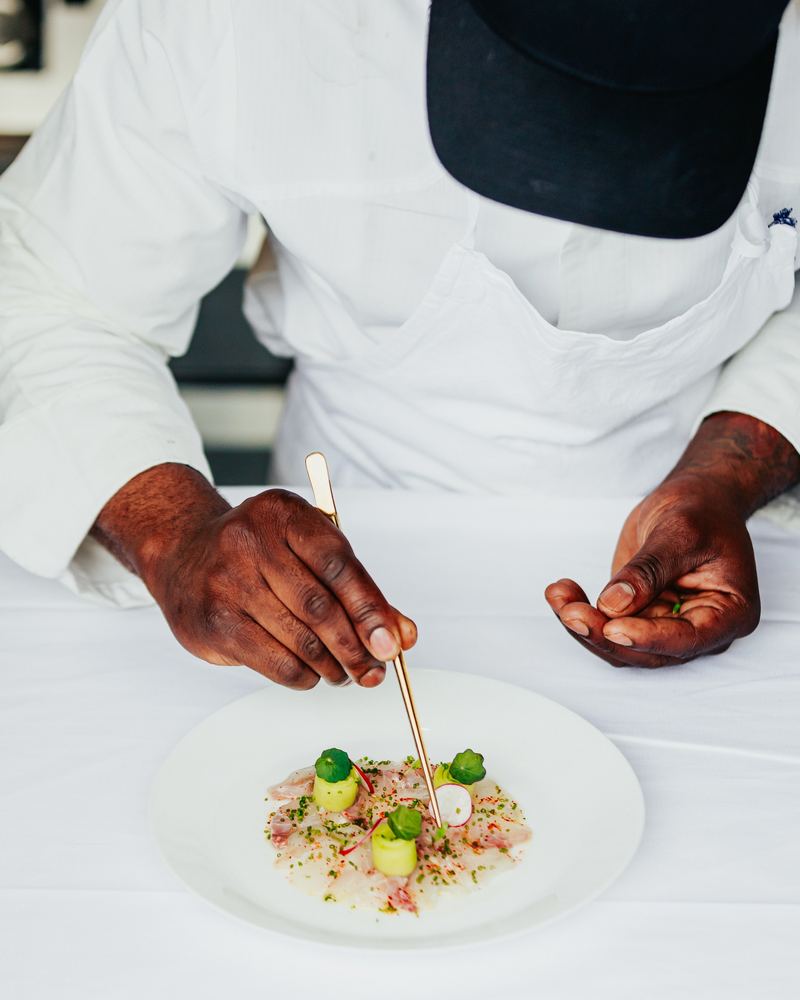 Le chef dispose des points de condiment à la pince sur un carpaccio