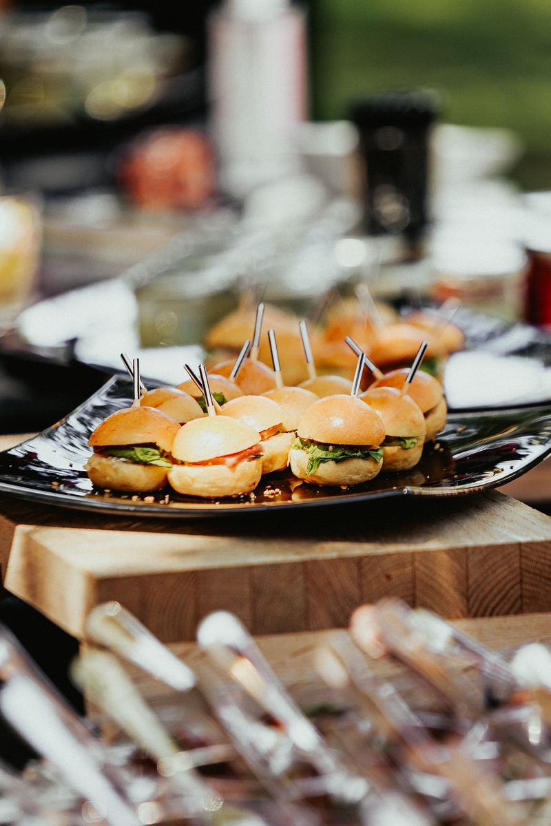Plateau de mini-burgers piqués de pics, dressé sur un buffet
