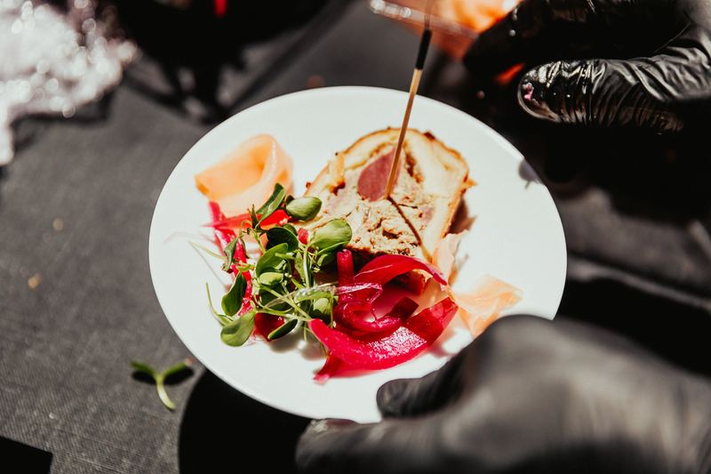 Le chef finalise le dressage d’une assiette, gants noirs et pince