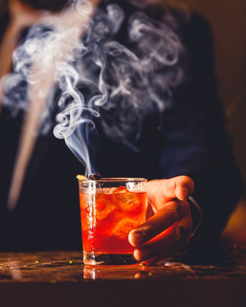 Cocktail fumant tenu à la main dans une lumière tamisée