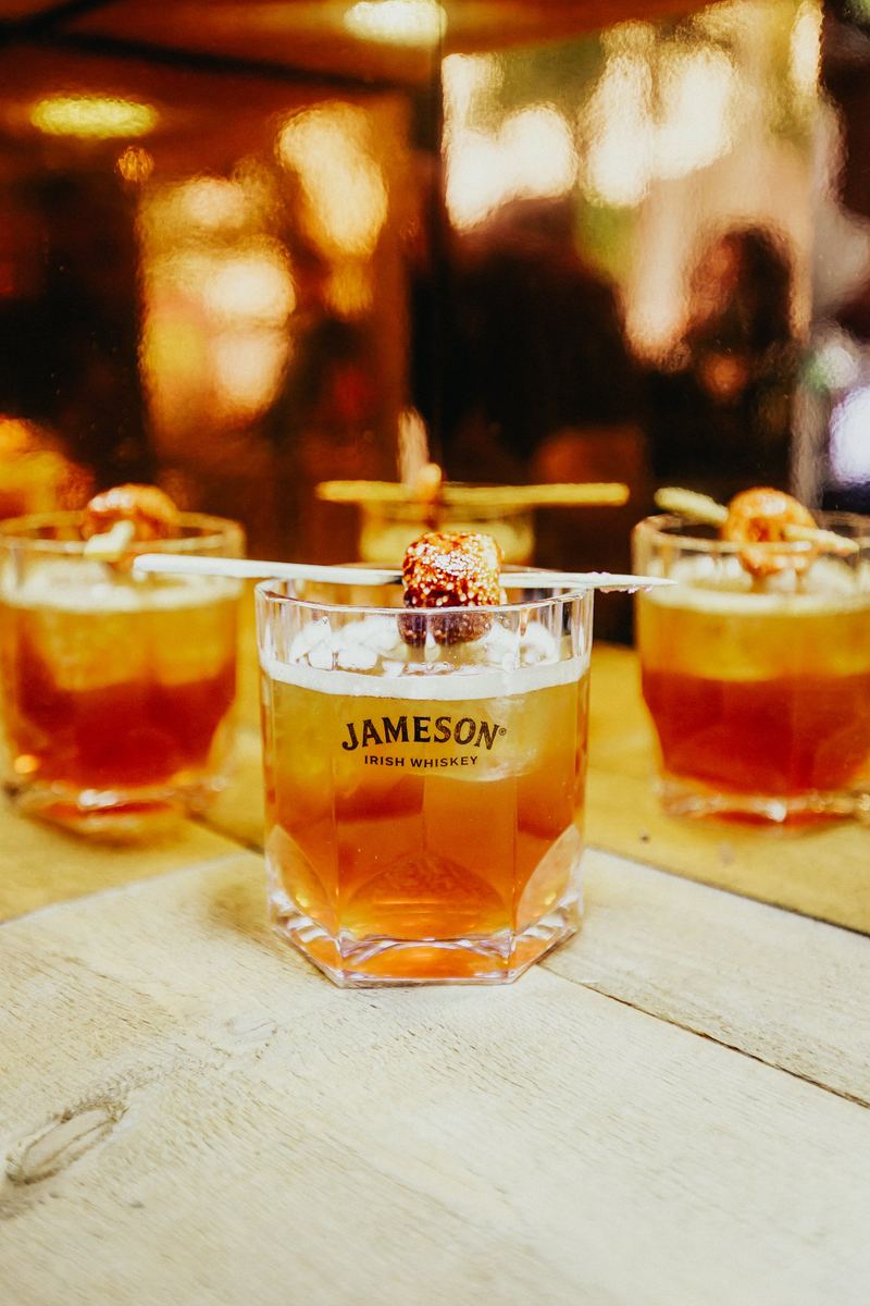 Cocktails au whisky servis sur un comptoir en bois, garniture épicée
