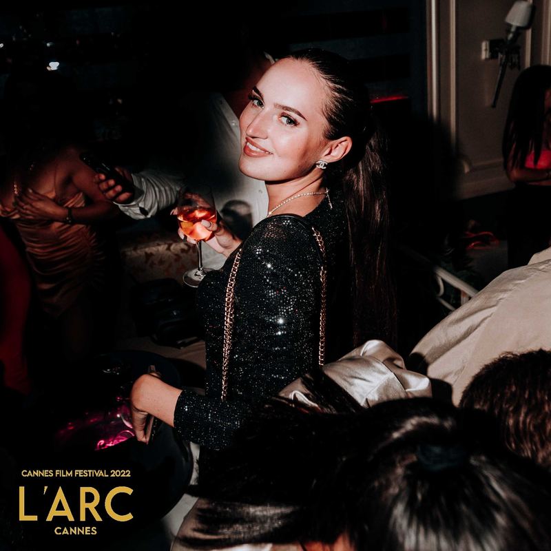 Invitée en robe pailletée se retourne, cocktail à la main