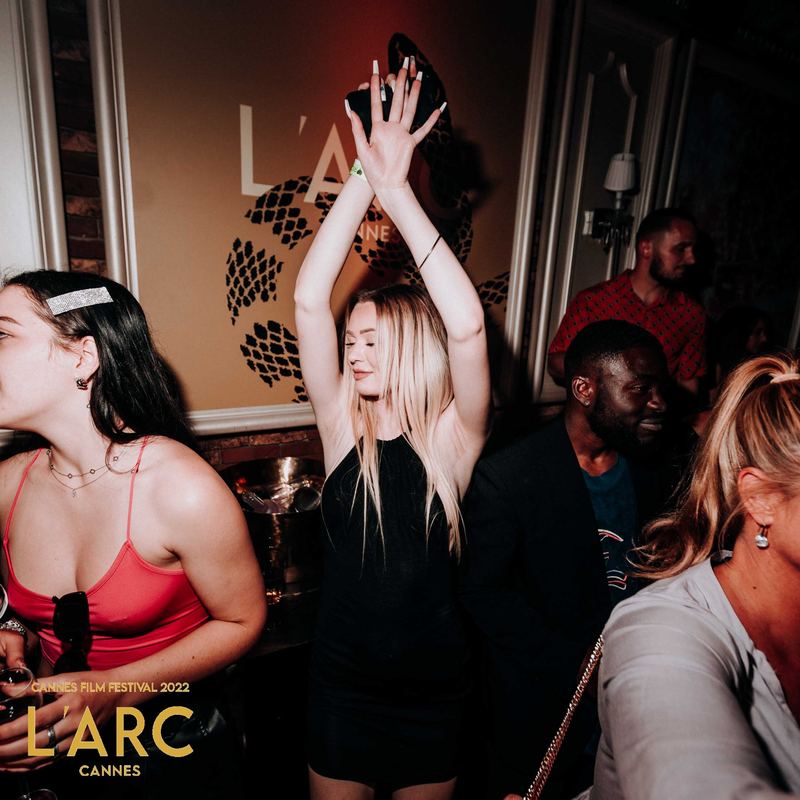 Invitée danse bras levés devant le mur du club