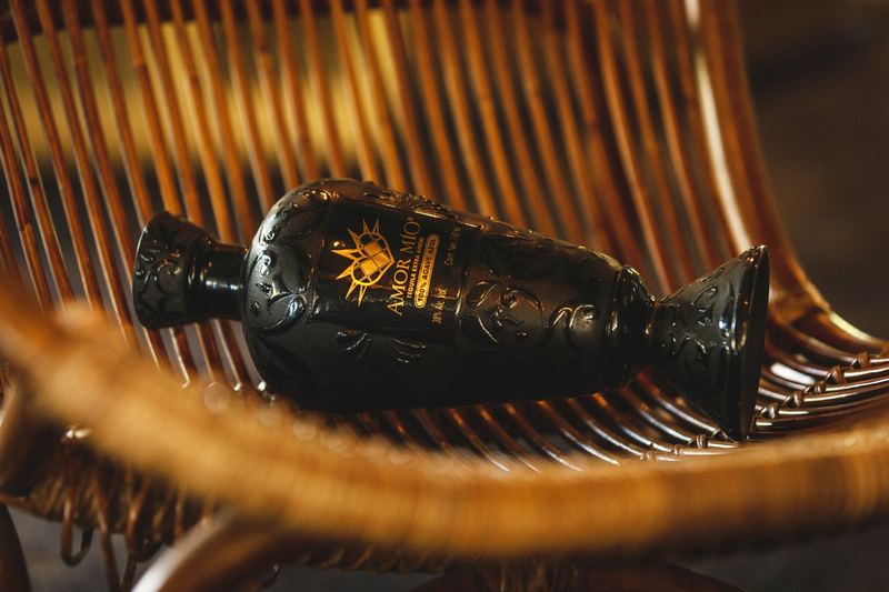 Bouteille noire couchée sur un fauteuil en rotin, lumière dorée