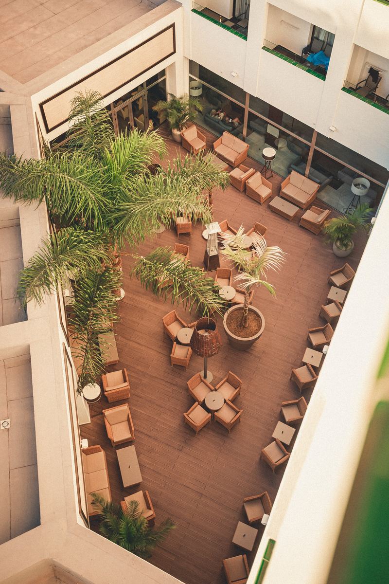 Patio intérieur de l’hôtel vu du dernier étage, transats et palmiers