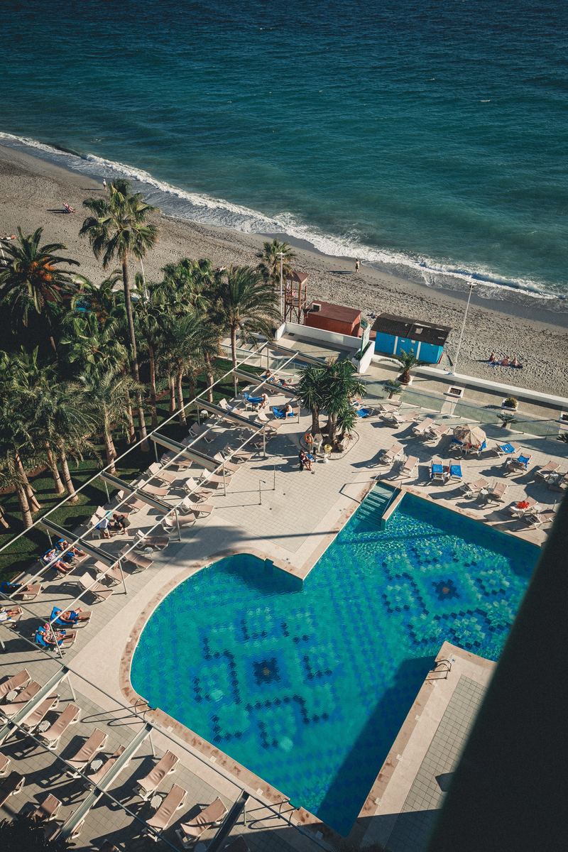 Piscine en mosaïque bleue au bord de la plage, vue du ciel