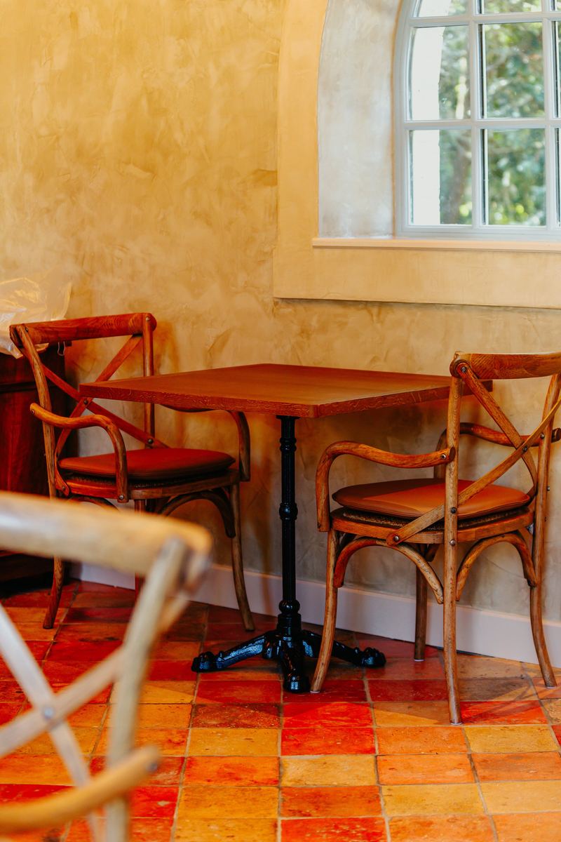 Table de bistrot et chaises en bois devant une fenêtre cintrée