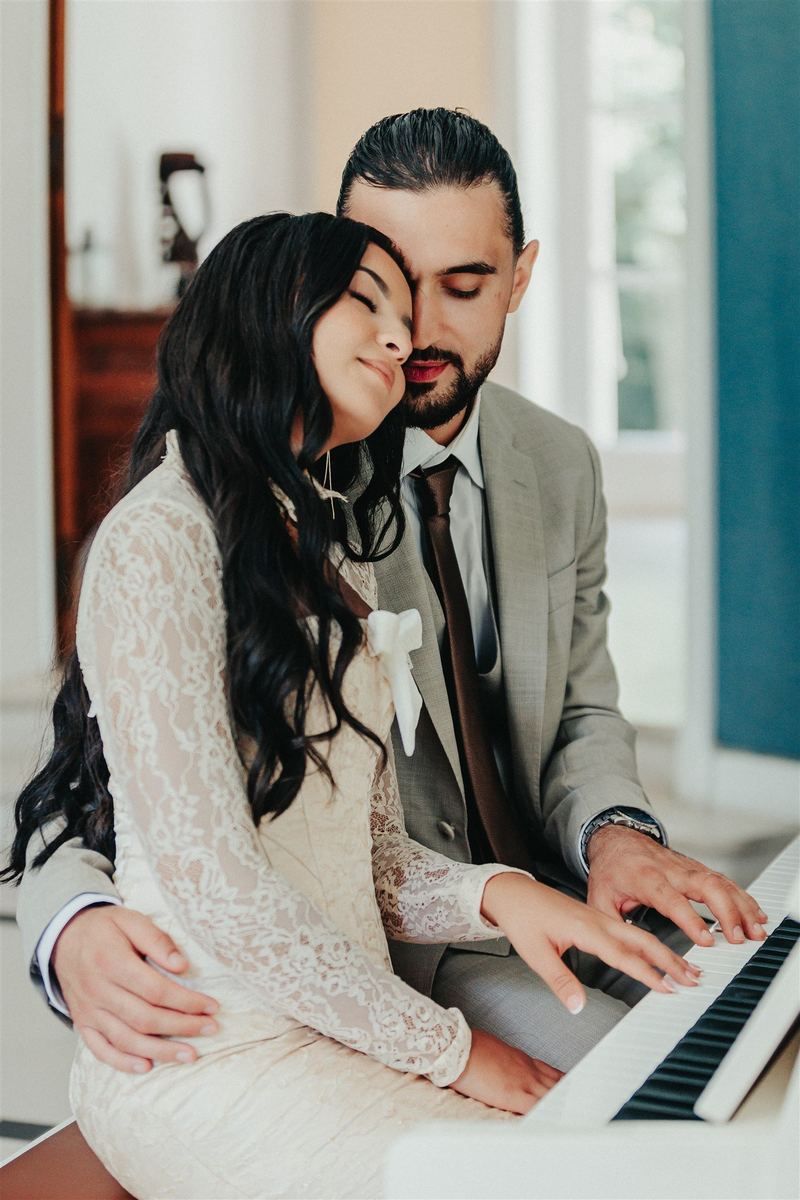 Les mariés au piano blanc, la mariée blottie contre l’épaule du marié